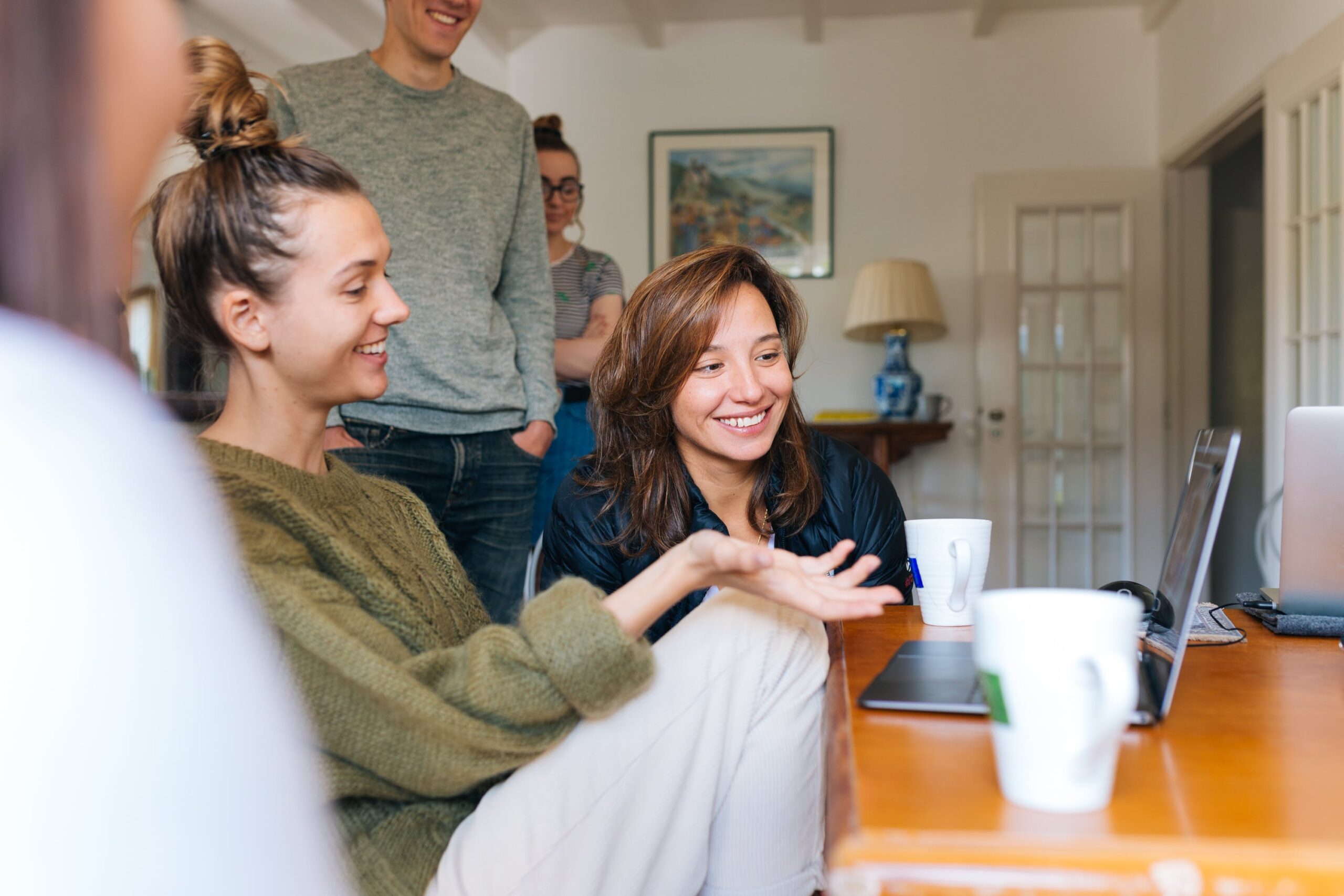 People looking happy at a laptop with drinks on the table