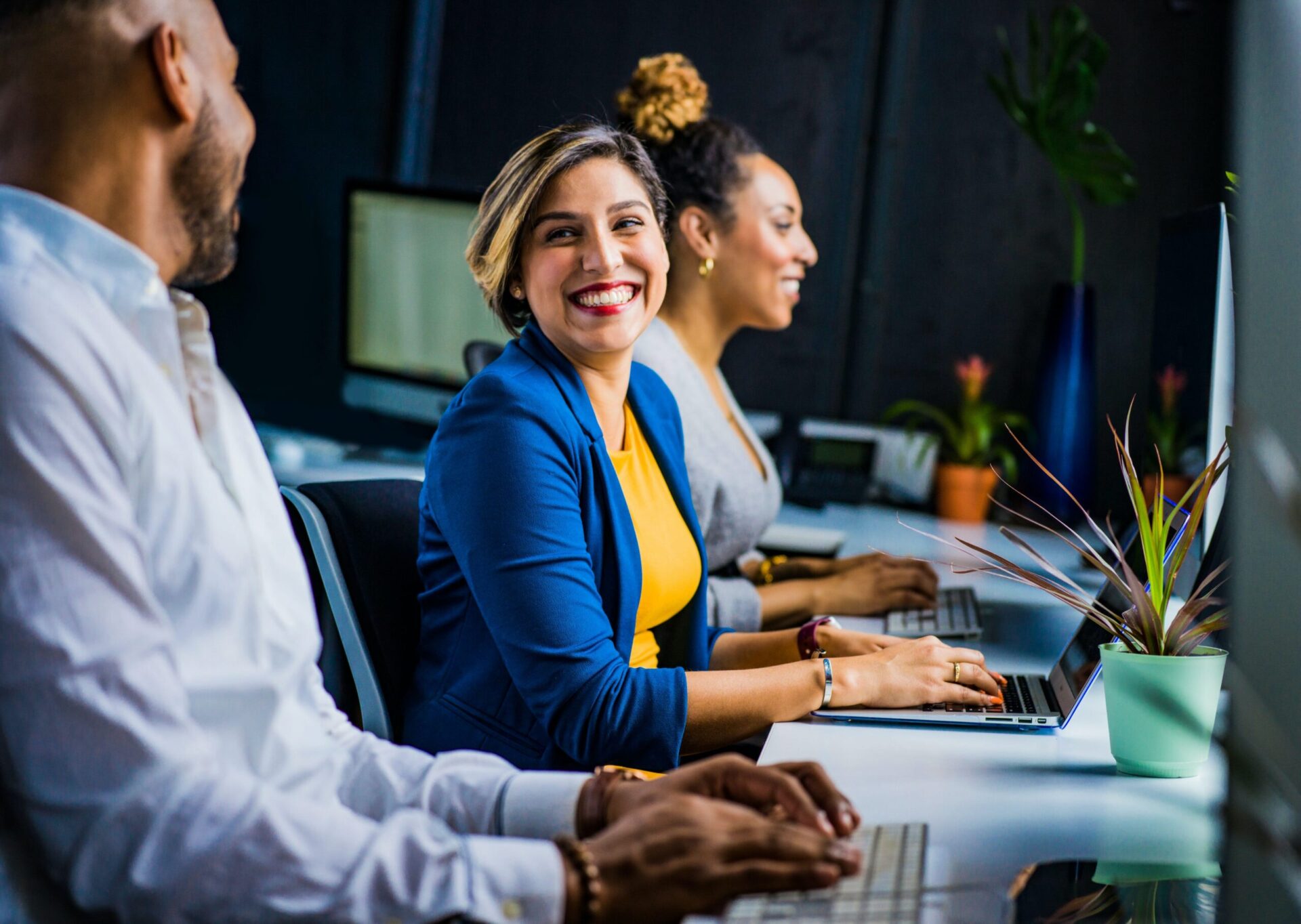 Woman smiling at work colleague while working on a laptop
